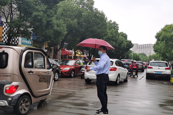 雨中的坚守——社区教育志愿者义务指挥交通.jpg